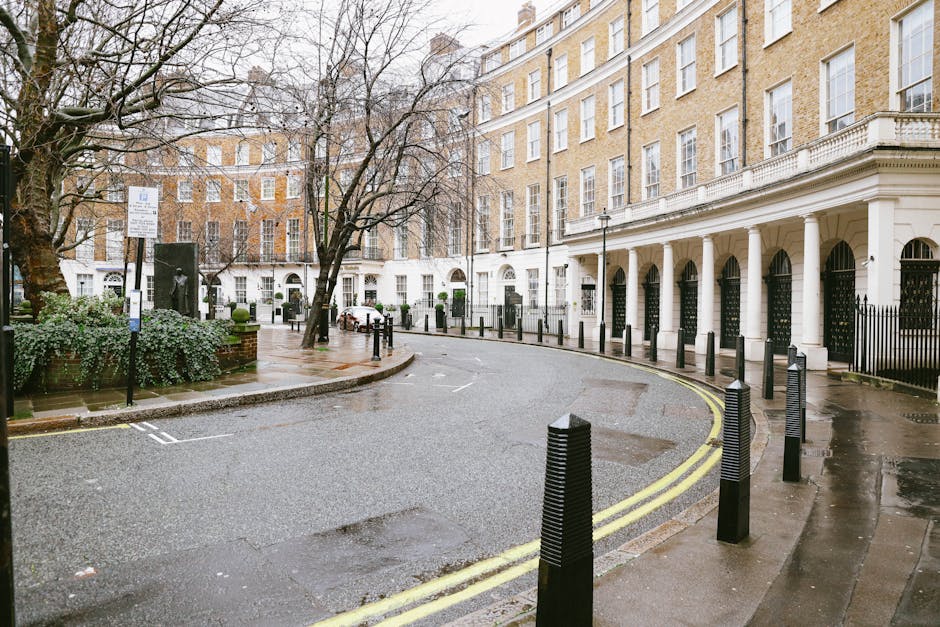 Urban street scene showing a multi-story brick and white plaster building with large windows, housing retail stores at ground level such as Pret A Manger and other shops. The sidewalk is bustling with pedestrians crossing the road, some carrying shopping bags or using smartphones. Several traffic lights and street lamps are visible, along with a street sign indicating Baker Street NW1. On the right, a modern building with glass balconies reflects daylight, enhancing the city atmosphere. The scene captures the lively atmosphere of Marylebone, highlighting the importance of surface cleaning and maintenance in busy commercial areas, which is a service provided by Cleaners Marylebone for deep cleaning and sanitisation of residential and commercial spaces.