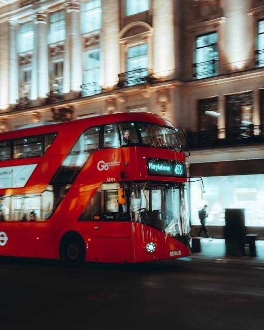 A red double-decker London bus parked on a city street in front of an ornate, historic building with large windows and decorative columns. The bus displays the route number 443 and the destination 'Ma